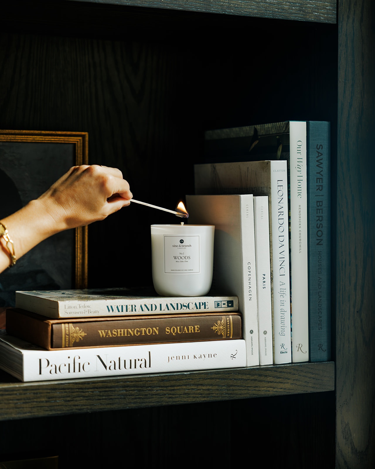 Lighting a Vine & Branch candle on a bookshelf